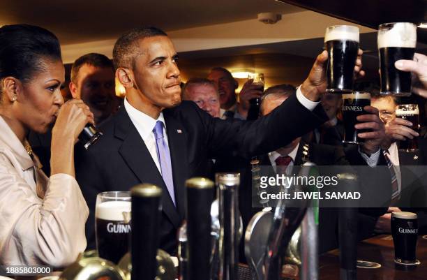 President Barack Obama and First Lady Michelle Obama sip Guinness at a pub as they visit Moneygall village in rural County Offaly, Ireland, where his...