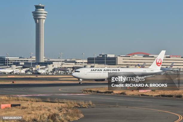 This photo taken on December 29, 2023 shows a Japan Airlines passenger plane taxiing past the control tower after its arrival at Tokyo International...
