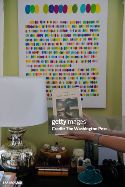 Celeste Ng holds her copy of "The Writing Life" by Annie Dillard in front of a painting that she made in code of a specific passage at her home in...