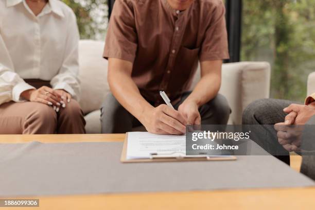 les acheteurs et l’agent immobilier examinent le contrat - annonce immobilière photos et images de collection