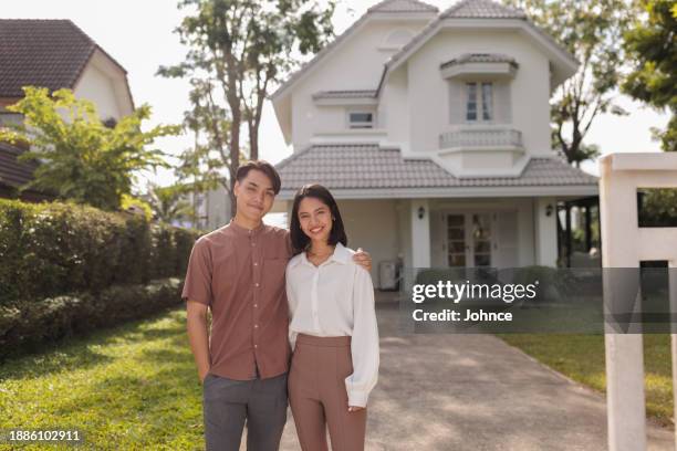 smiling couple in front of their new house - home owner stock pictures, royalty-free photos & images