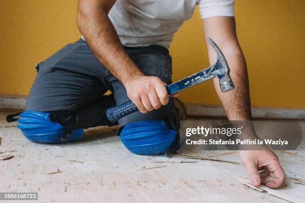 construction worker using hammer - knieschützer stock-fotos und bilder