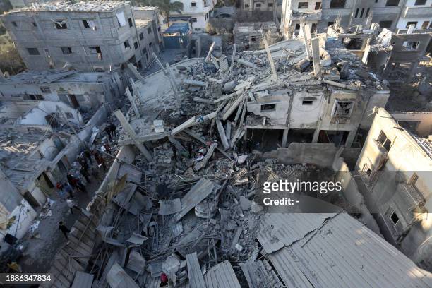 Palestinians inspect the damage following Israeli strikes on the Zawayda area of the central Gaza Strip on December 30 amid ongoing battles between...