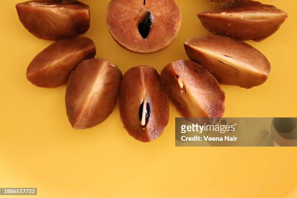 manilkara zapota/sapodilla fruit kept in a row against yellow background - chicle stockfoto's en -beelden