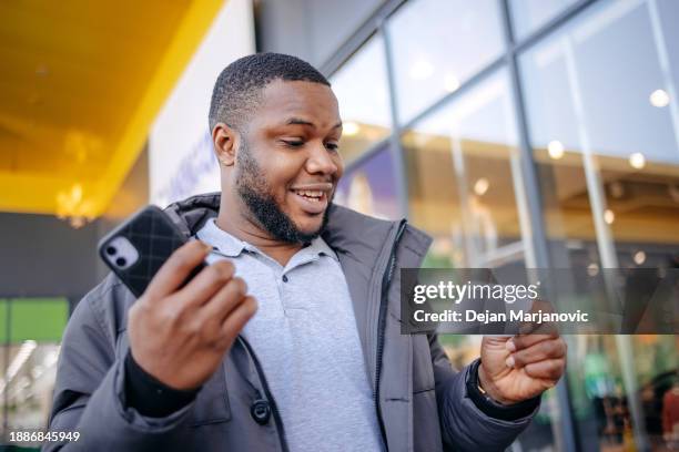 young man finds out that he has winning ticket in hands. surprised and happy face while walking outdoors. - jackpot stock pictures, royalty-free photos & images