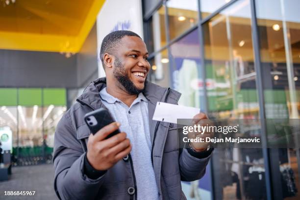 el joven descubre que tiene el boleto ganador en las manos. cara de sorpresa y felicidad mientras caminaba al aire libre. - billete-de-lotería fotografías e imágenes de stock