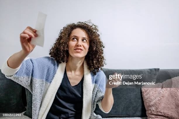 woman finds out that she has winning ticket in hands. surprised and happy face at home. - mid adult women imagens e fotografias de stock