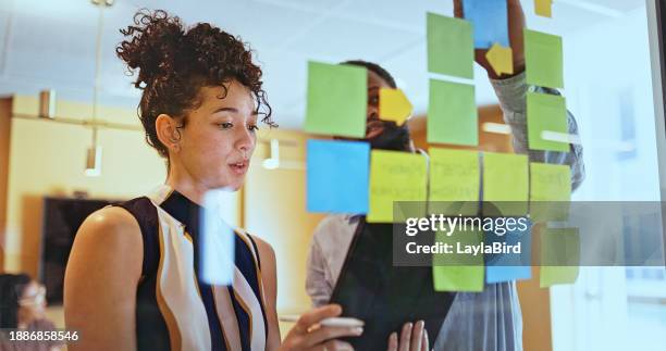 jeune femme d’affaires tenant une tablette numérique lisant des plans de travail à un collègue dans la salle de réunion - digital post it note photos et images de collection