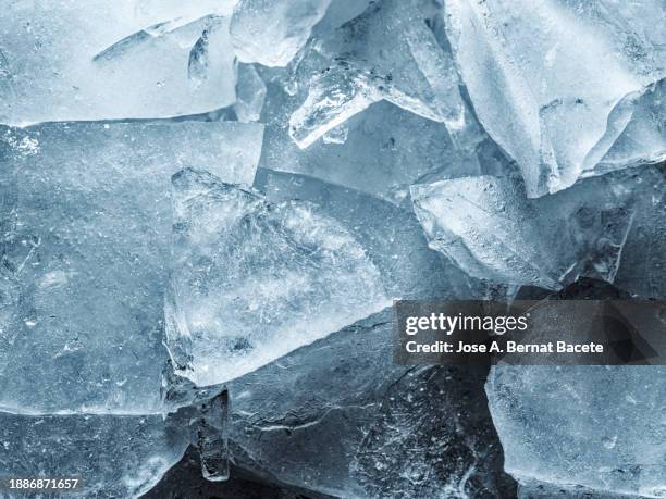 full frame, frozen water surface in a river with cracks and broken ice crystals of blue color. - glaçage photos et images de collection