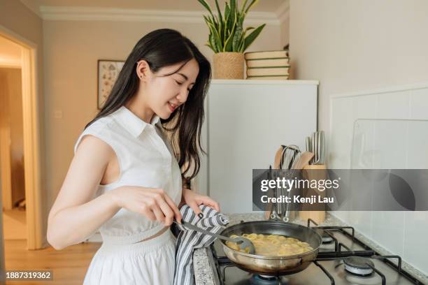 young asian woman preparing pasta on cooking stove in kitchen at home. cooking, and people lifestyle concept. - hot housewives stock pictures, royalty-free photos & images