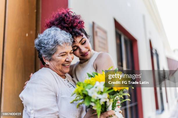 grandmother receiving a bouquet of flowers from her granddaughter outdoors - mothers day flowers stock pictures, royalty-free photos & images
