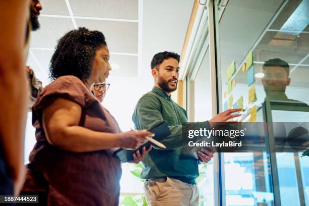 diverse professionals brainstorming on a glass wall - strategy execution stock pictures, royalty-free photos & images