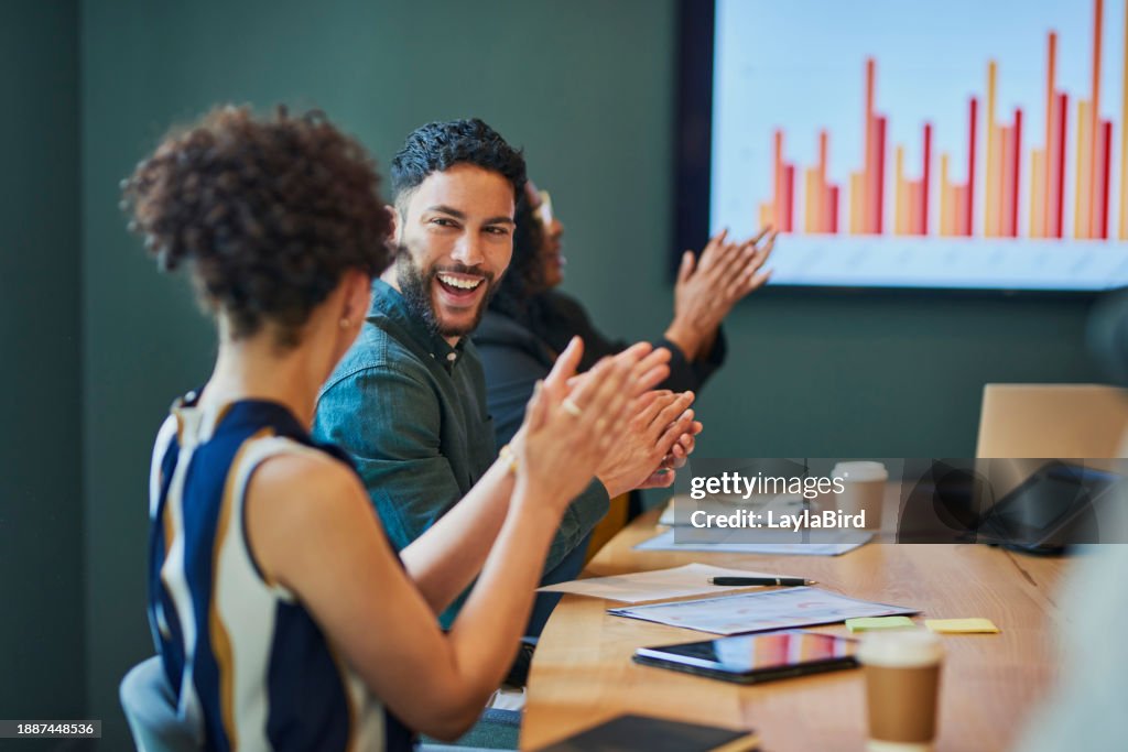 Group of business professionals clapping and smiling during a meeting in the boardroom.