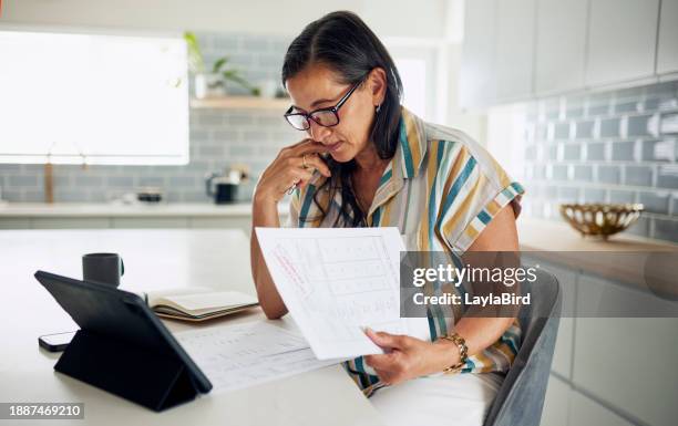 focused latina woman reading documents at home - tax scrutiny stock pictures, royalty-free photos & images