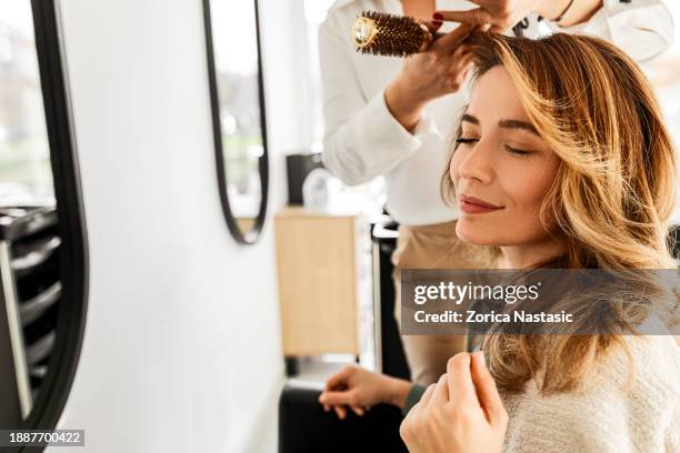coiffeur créant une belle finition avec le séchage - salon de beauté photos et images de collection