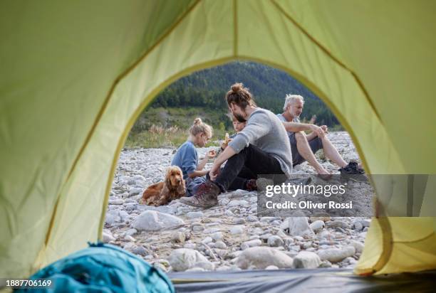 family sitting on pebbles outside tent - multi generational family with pet stock pictures, royalty-free photos & images