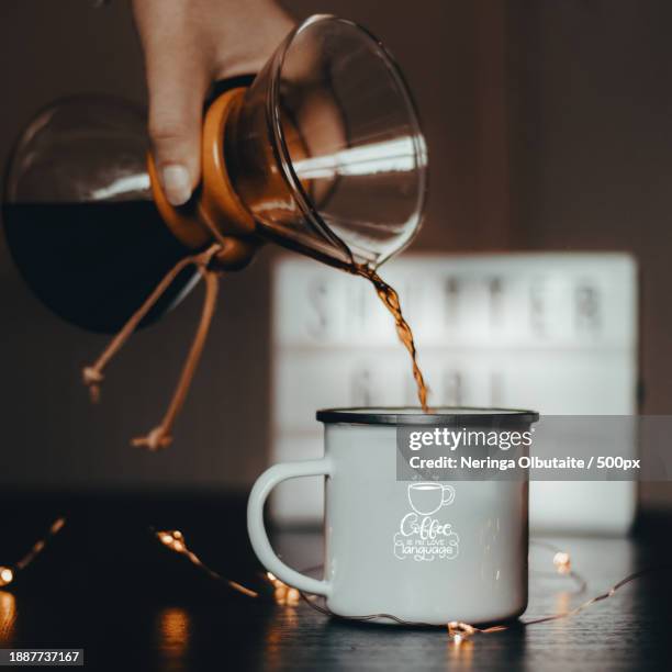 cropped hand pouring drink in cup on table,united kingdom,uk - neringa fotografías e imágenes de stock