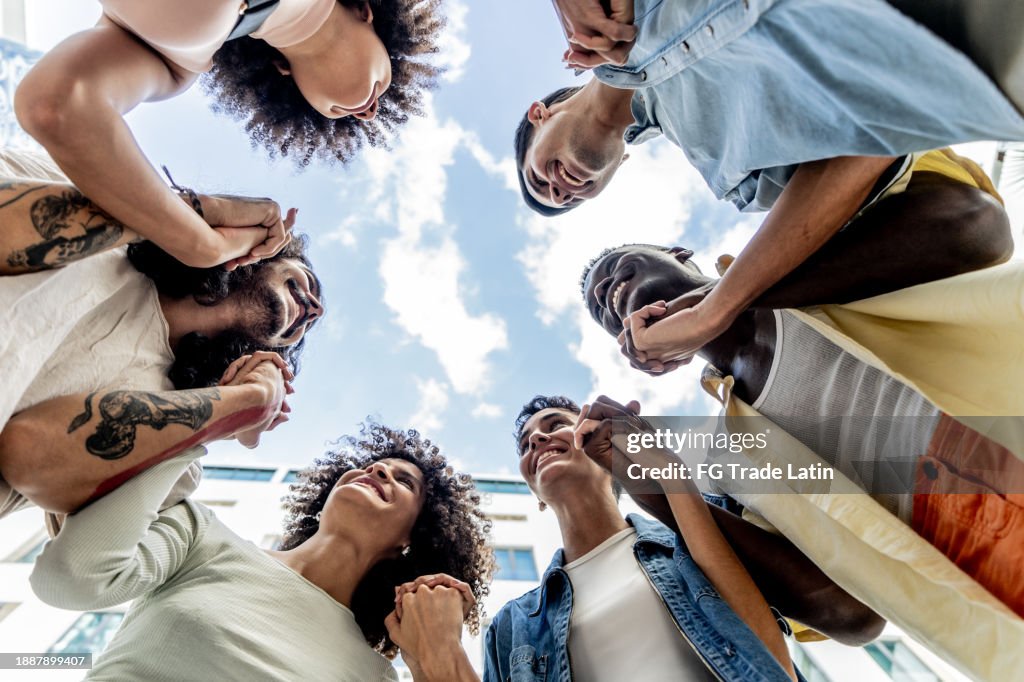 Friends with holding hands outdoors - low angle view