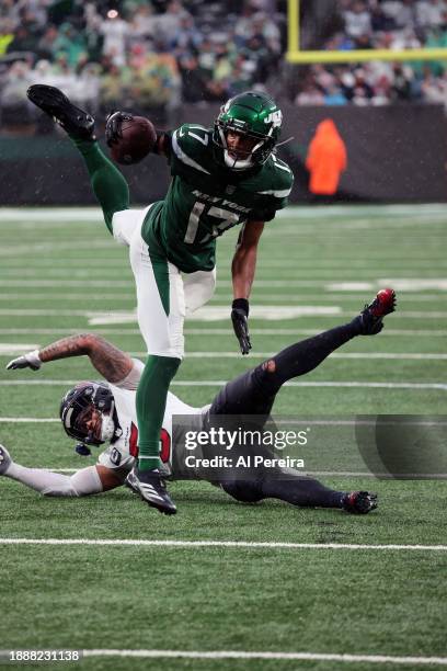 Wide Receiver Garrett Wilson of the New York Jets has a long gain and leaps over a defender in the game in the rain between the Houston Texans vs the...