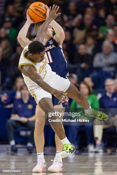 Markus Burton of the Notre Dame Fighting Irish is tripped up going for the ball against Isaac McKneely of the Virginia Cavaliers during the second...