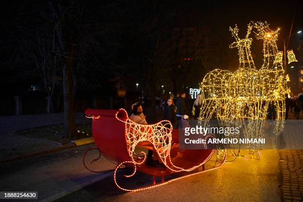 Children sit on an illuminated sleigh displayed in downtown Pristina on December 30 ahead of the New Year celebrations in Kosovo.