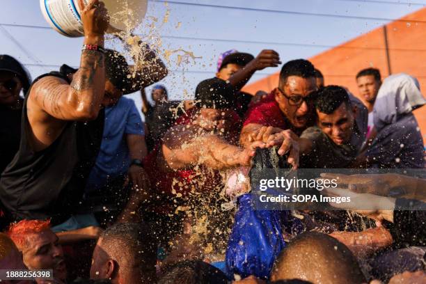People are seen throwing rum at the statue of San Benito as a sign of devotion during the procession. The San Benito festival is celebrated in...