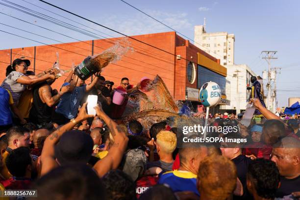 People are seen throwing rum at the statue of San Benito as a sign of devotion during the procession. The San Benito festival is celebrated in...