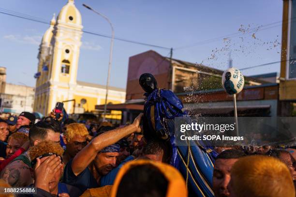 The crowd is seen throwing rum at the statue with the Cabimas cathedral in the background. The San Benito festival is celebrated in Cabimas within...