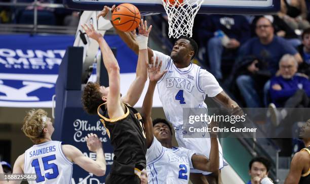 Atiki Ally Atiki of the Brigham Young Cougars flys over teammate Jaxson Robinson to block a shot by Mason Walters of the Wyoming Cowboys during the...