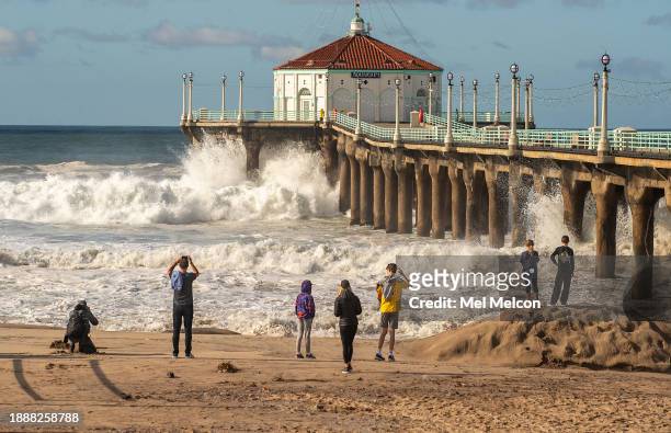 People watch and photograph as another large wave crashes against the Manhattan Beach Pier. The pier was closed to the public due to the high surf.