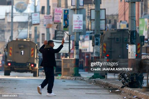 Palestinian man walks with his hands up in the air as he approaches military vehicles during an Israeli raid in the Askar refugee camp, east of the...