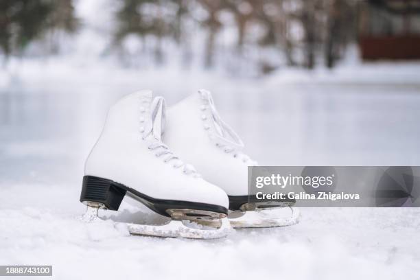 pair of white women's figure skates on ice rink in the park - figure skating pair stock pictures, royalty-free photos & images