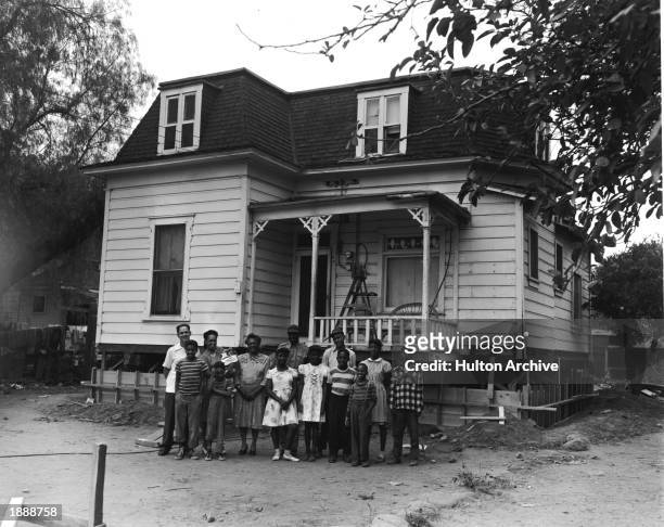 American baseball player Jackie Robinson , wearing a military uniform, stands with members of his family outside his boyhood home at 121 Pepper...