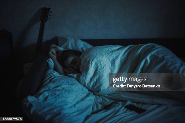 young woman sleeping in bed at night - dark bedroom bed stock pictures, royalty-free photos & images