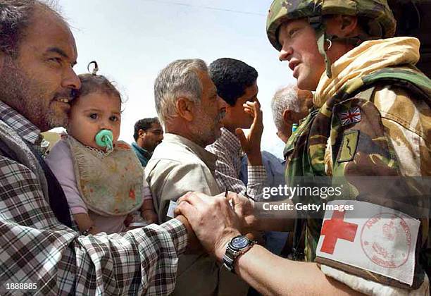 In this handout photo from Central Command, Colonel Dunken Robertson of 4 General Support Regiment Medics, provides medical attention to a father of...