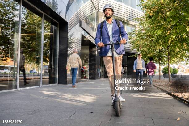 hombre montando su e-scooter en la carretera en la ciudad - movilidad sostenible fotografías e imágenes de stock