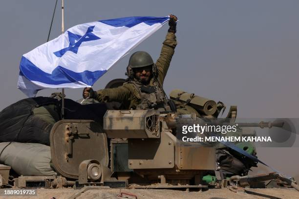 This photograph taken near the border with the Gaza Strip shows an Israeli soldier on an armoured personnel carrier waving an Israeli flag as troops...