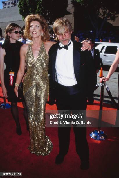 American actress and singer Christine Baranski, wearing a gold halterneck evening gown, and her husband, American actor and playwright Matthew...