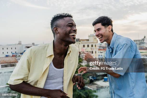 friends talking and laughing on the rooftop - mannelijke vriendschap stockfoto's en -beelden