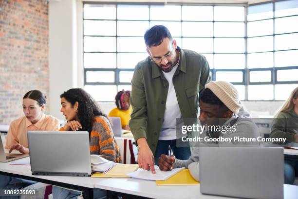 lehrer, der einem männlichen college-studenten während eines unterrichts hilft - technische hochschule stock-fotos und bilder