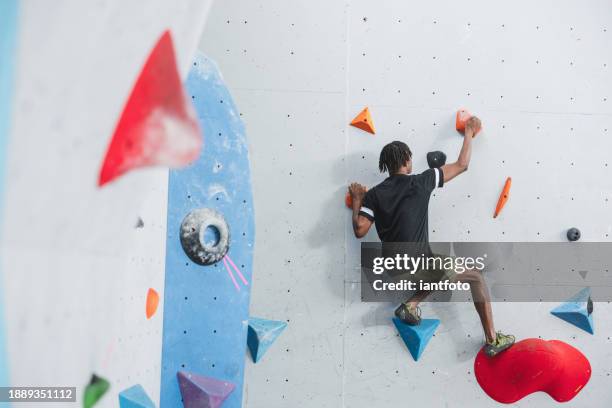 athletic african american man climbing in a colorfull indoor wall. - klimsport stockfoto's en -beelden