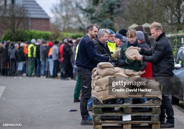 Volunteers hand on sandbags to the operation area during the flood at the river Ems on December 31, 2023 in Haren, Germany. Authorities and emergency...