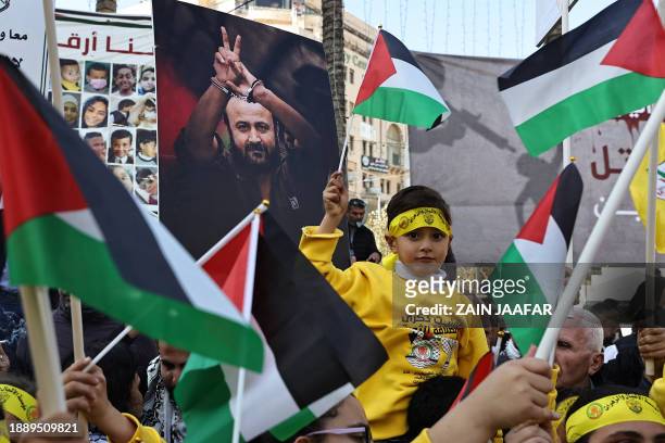 Palestinians lift flags during a rally marking the 59th anniversary of the Fatah movement foundation in Ramallah in the occupied West Bank on...