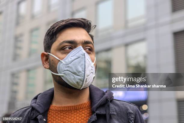 return of covid jn.1 , man wearing n95 face mask - n95 respirator mask stock-fotos und bilder