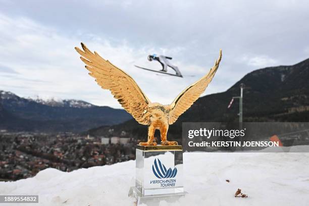 The overall winners' trophy is pictured as an athlete soars through the air on the sidelines of the second stage of the Four-Hills tournament that is...