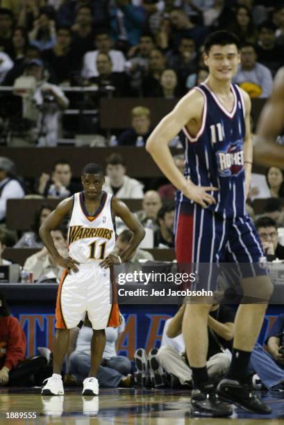 Earl Boykins of the Golden State Warriors and Yao Ming of the Houston Rockets rest during the game at The Arena in Oakland on March 21, 2003 in...