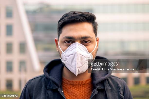 return of covid jn.1 , man wearing n95 face mask - n95 respirator mask stock-fotos und bilder