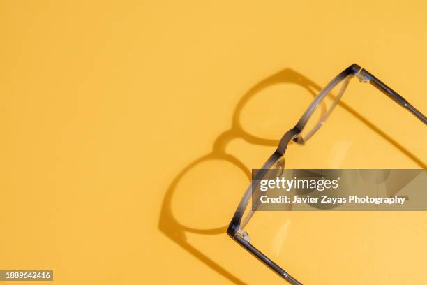 blue modern eyeglasses on yellow background - miopia foto e immagini stock