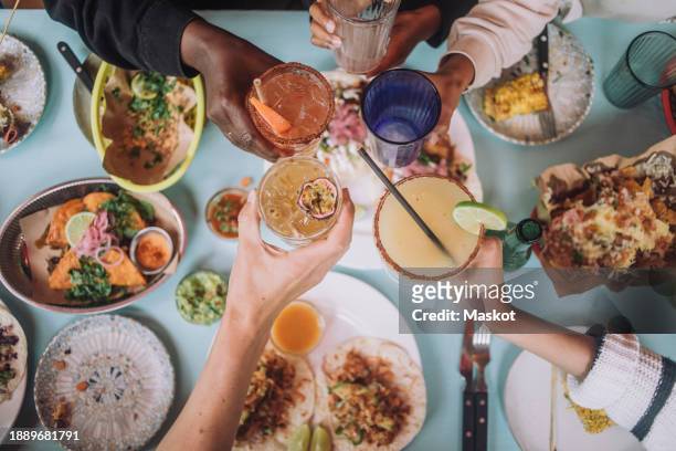 directly above view of hands toasting glass of fresh cocktails while celebrating at restaurant - food stock pictures, royalty-free photos & images
