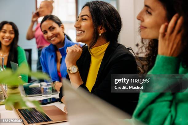 smiling female business professional with colleagues during meeting at office - indischer abstammung stock-fotos und bilder